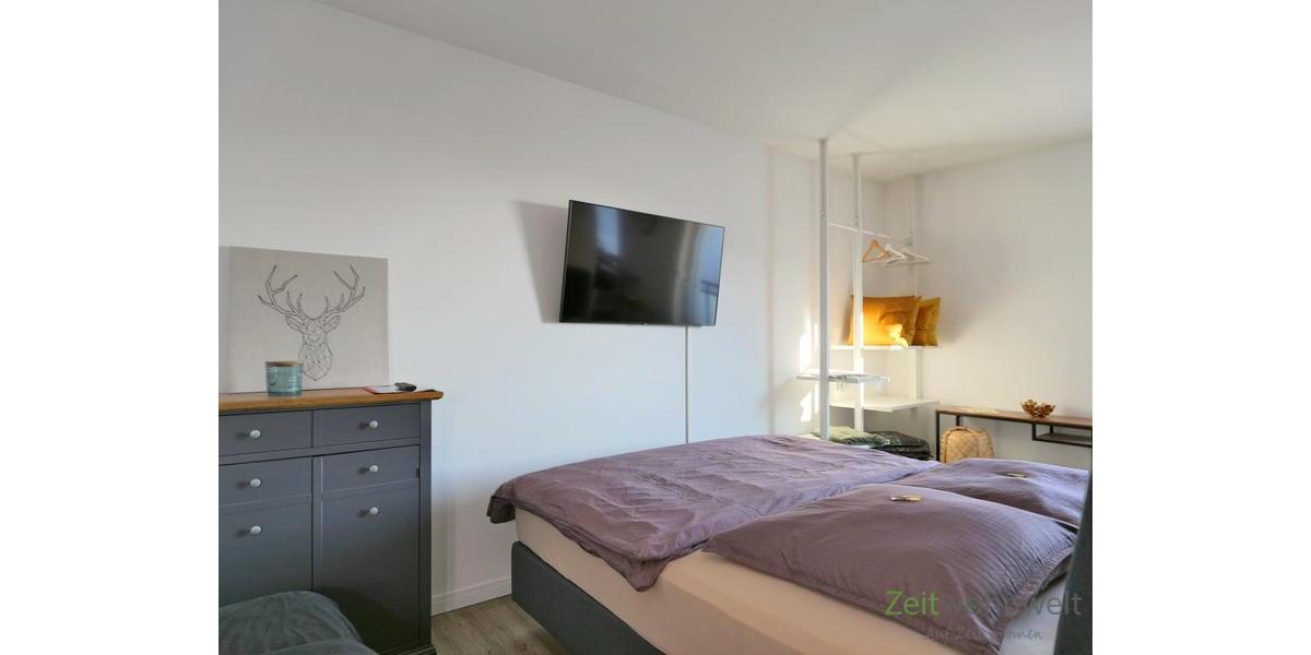 Doppelbett und TV hinter dem Raumteiler